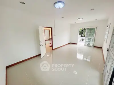 Spacious and bright living room with balcony access and modern tile flooring.