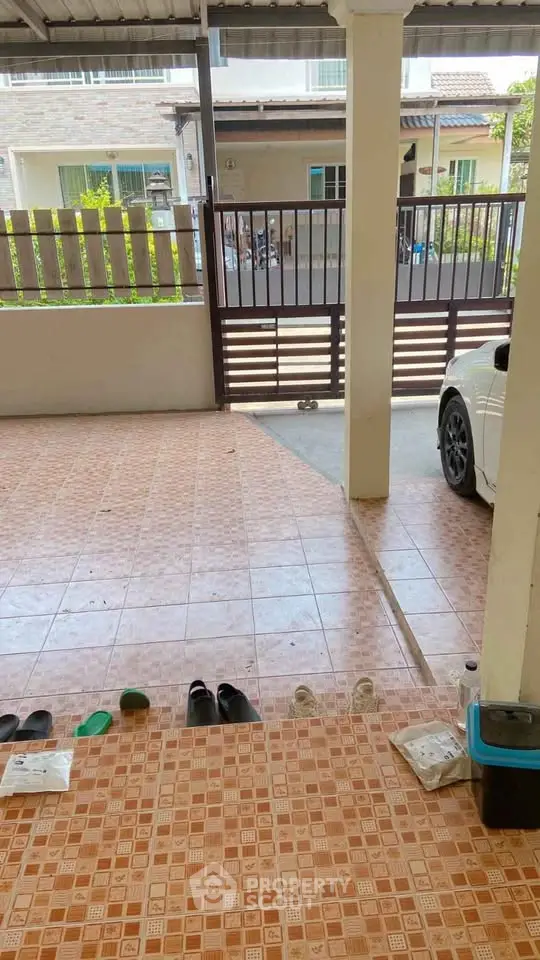 Spacious covered parking area with tiled flooring and gated entrance in a residential property.