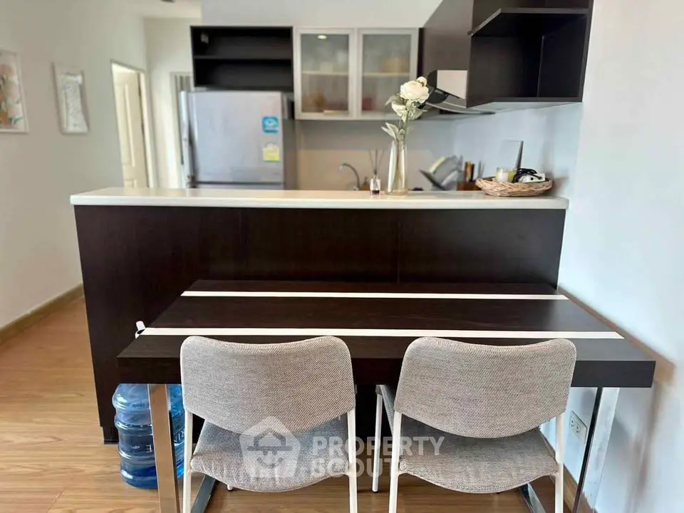 Modern kitchen with sleek design and dining area, featuring stylish chairs and a spacious fridge.