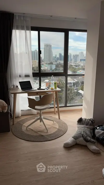 Modern study area with city view, featuring a sleek desk and comfortable chair by large windows.