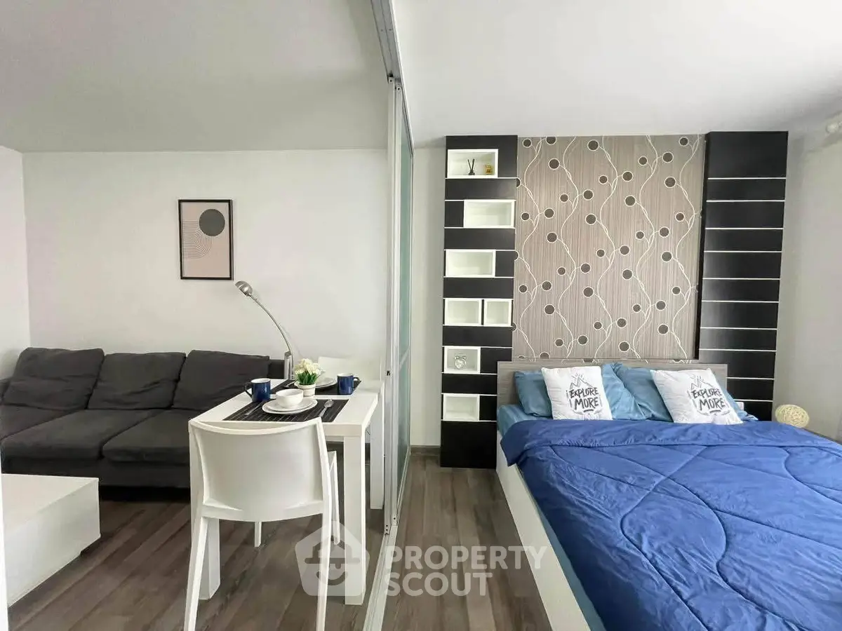 Modern studio apartment with stylish decor, featuring a cozy bed and a comfortable living area.