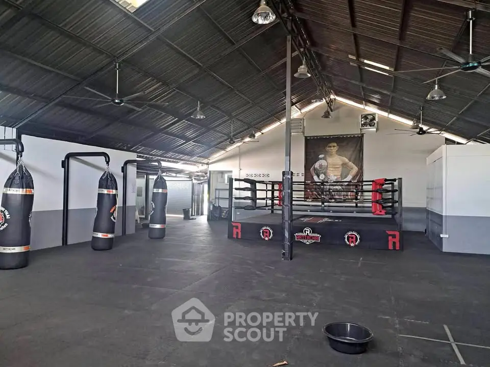 Spacious gym with boxing ring and punching bags, ideal for fitness enthusiasts.