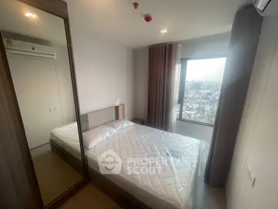 Modern bedroom with city view, featuring a comfortable bed and large window for natural light.