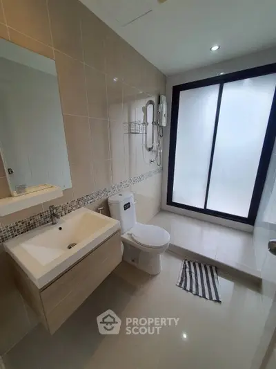 Modern bathroom with sleek fixtures and large frosted glass shower area.
