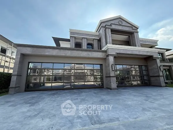 Luxurious modern mansion with expansive glass garage doors and elegant architecture.