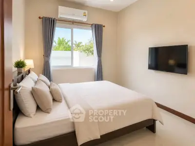 Modern bedroom with large window, air conditioning, and wall-mounted TV in a cozy home.