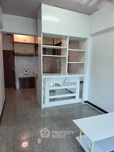 Spacious open-plan living area with built-in shelving and modern kitchen design.