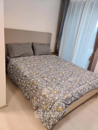Cozy bedroom with stylish decor and natural light from large window, perfect for relaxation.