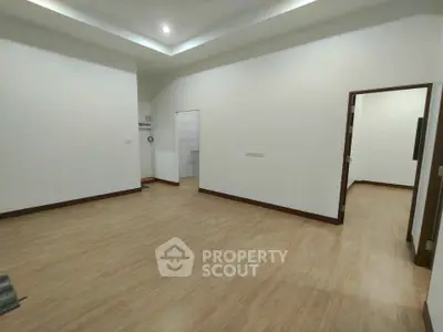 Spacious empty room with wooden flooring and recessed lighting, ideal for customization.