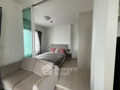 Modern bedroom with cozy bed and sofa, featuring natural light and stylish decor.