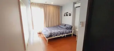 Cozy bedroom with wooden flooring and natural light, featuring a comfortable bed and air conditioning.