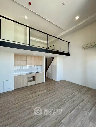 Spacious modern loft with open kitchen and mezzanine in a bright, airy apartment.
