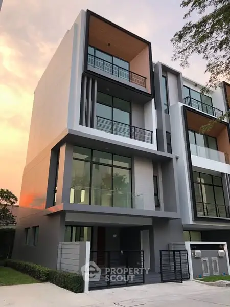 Modern multi-story building with large windows and sleek design at sunset.
