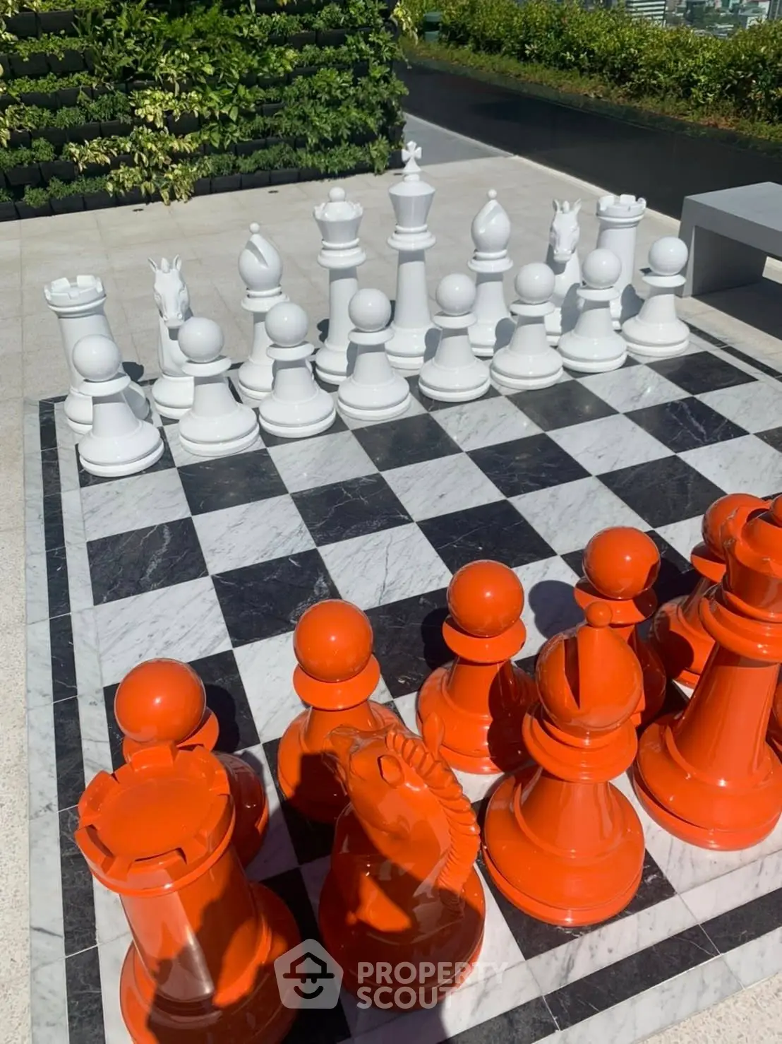 Rooftop garden with large outdoor chess set and lush greenery.