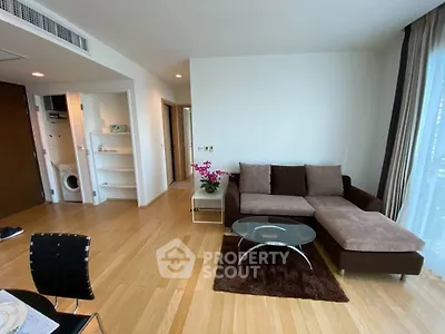 Modern living room with hardwood floors, cozy sectional sofa, and natural light from large windows.