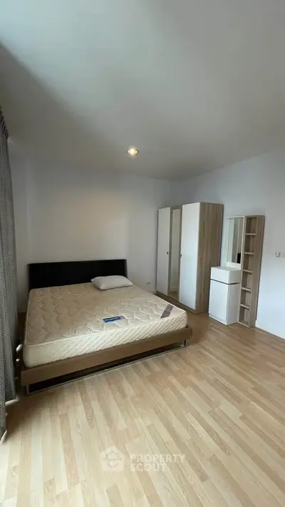 Spacious bedroom with modern furnishings and wooden flooring in a cozy apartment.