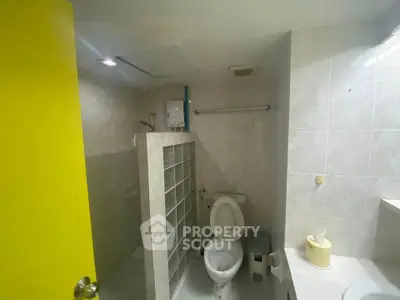 Compact bathroom with shower and bright yellow door
