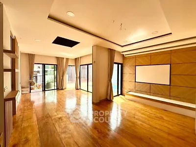 Spacious modern living room with wooden flooring and large windows for natural light.