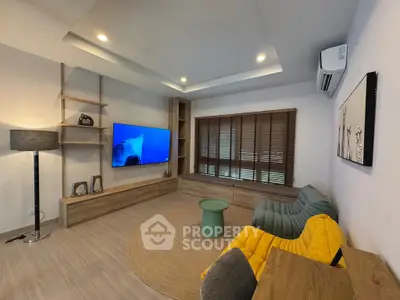 Modern living room with stylish furniture and large TV, featuring cozy seating and elegant lighting.