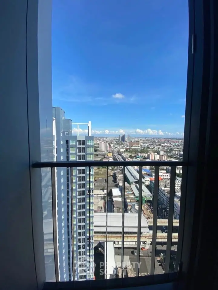 Stunning high-rise city view from a modern apartment balcony, showcasing urban skyline and blue skies.