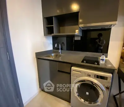 Modern compact kitchen with sleek cabinetry and built-in washing machine
