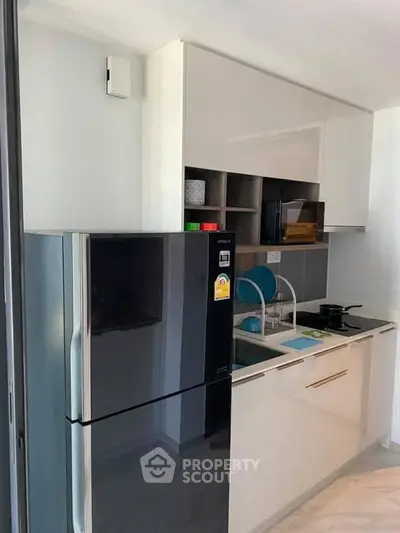 Modern kitchen with sleek cabinetry and stainless steel fridge in a compact layout.