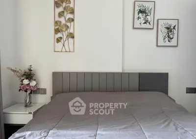 Modern bedroom with stylish decor and elegant wall art, featuring a cozy bed and nightstand with floral arrangement.