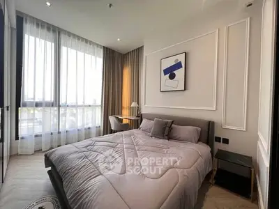 Modern bedroom with stylish decor and large windows offering natural light.