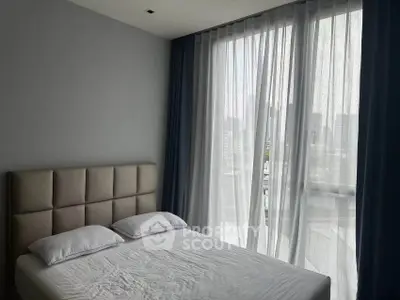 Modern bedroom with large window and city view, featuring a stylish headboard and elegant curtains.