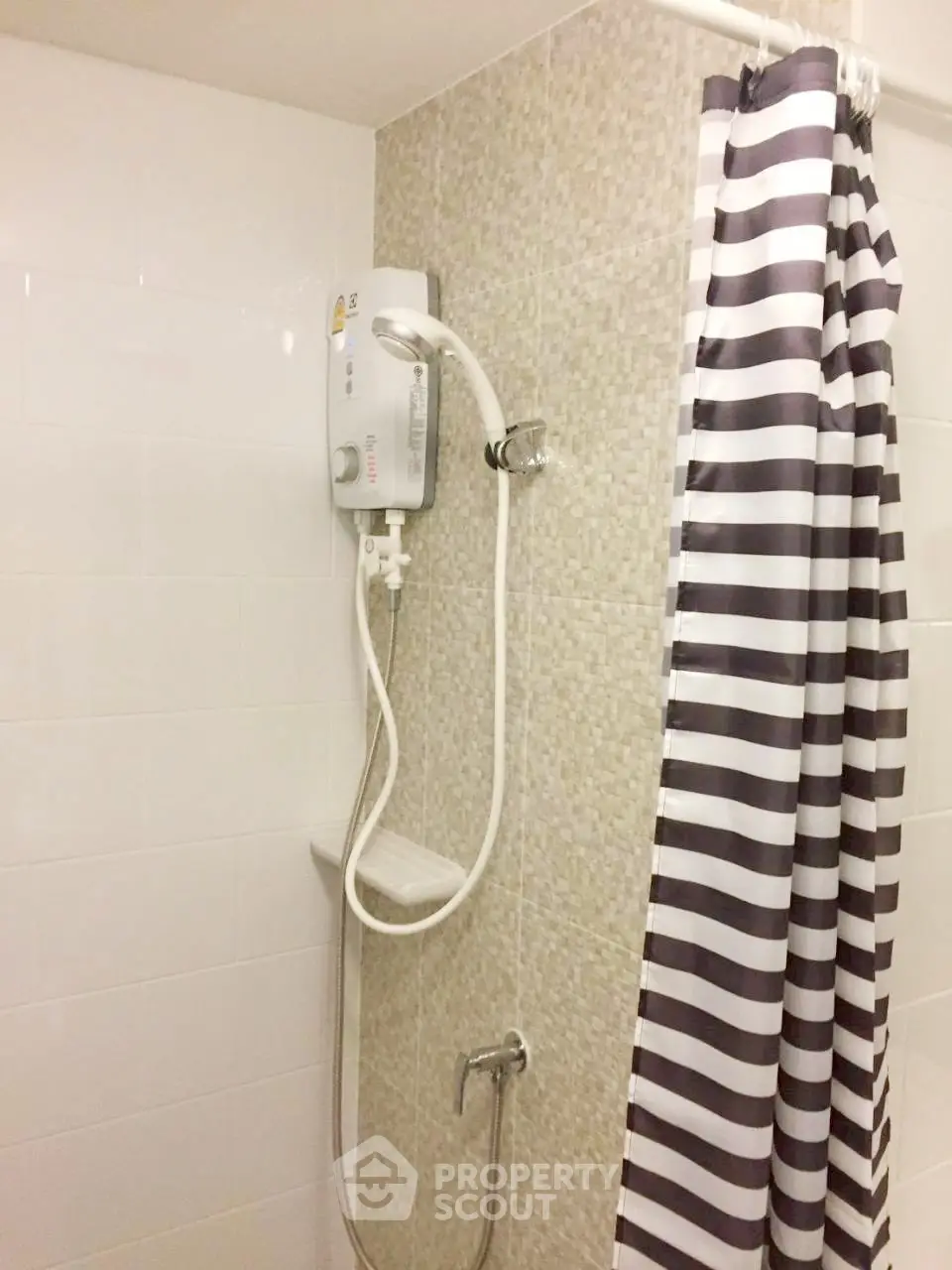 Modern bathroom with electric shower and striped curtain