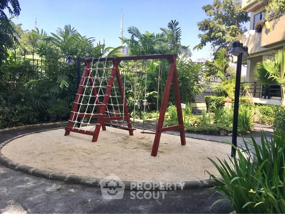 Charming outdoor playground area with climbing frame surrounded by lush greenery in a residential complex.