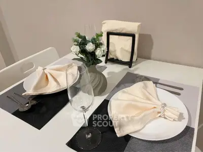 Elegant dining setup with white plates, napkins, and wine glasses on a modern table.