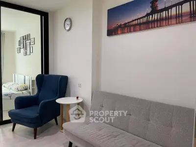 Modern living room with stylish furniture and wall art, featuring a cozy blue armchair and sleek gray sofa.