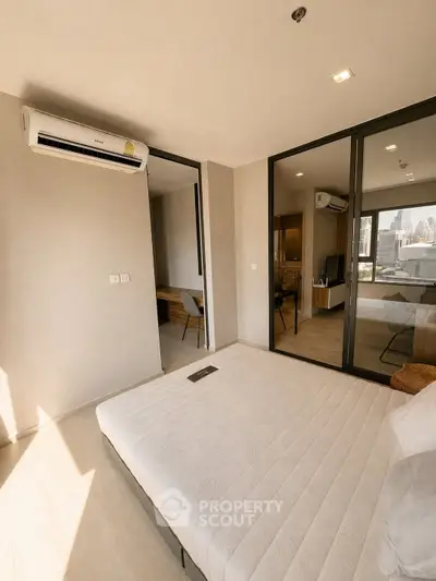 Modern bedroom with large windows and city view, featuring air conditioning and minimalist decor.