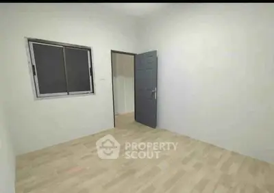Minimalist empty room with wooden flooring and single window