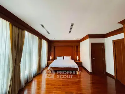 Spacious bedroom with elegant wooden flooring and large windows for natural light.