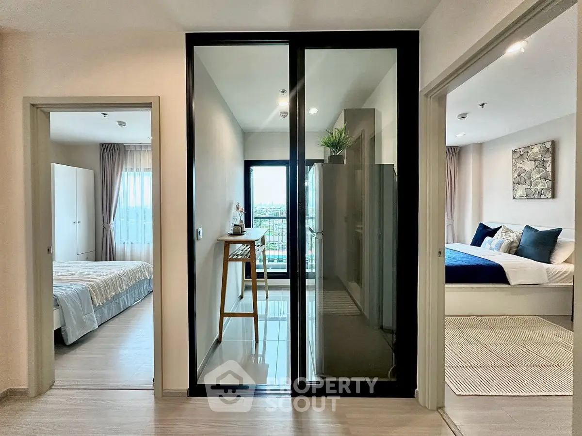 Modern apartment interior with two bedrooms and a stylish glass-enclosed balcony offering a scenic view.