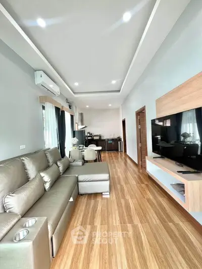 Spacious modern living room with sleek design and open layout, featuring a large sectional sofa and wall-mounted TV.