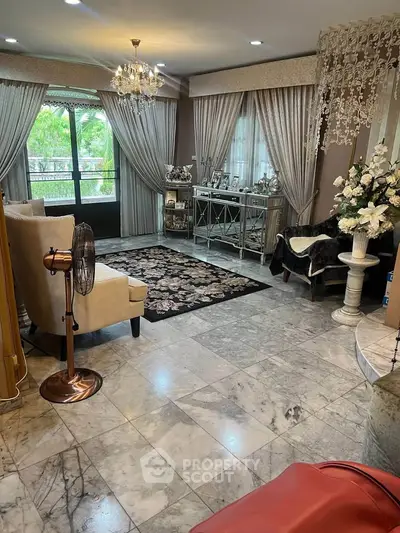 Luxurious living room with elegant decor, marble flooring, and large windows offering a serene garden view.