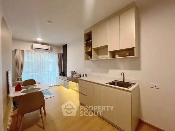 Modern kitchen with sleek cabinetry and dining area in cozy apartment