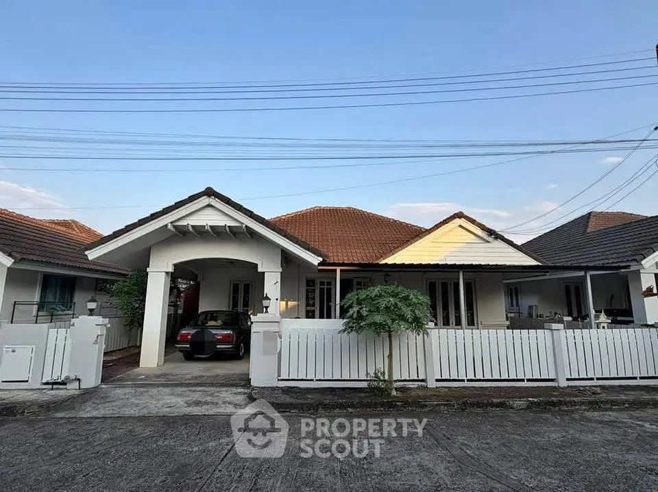 Charming single-story house with a carport and white picket fence in a serene neighborhood.