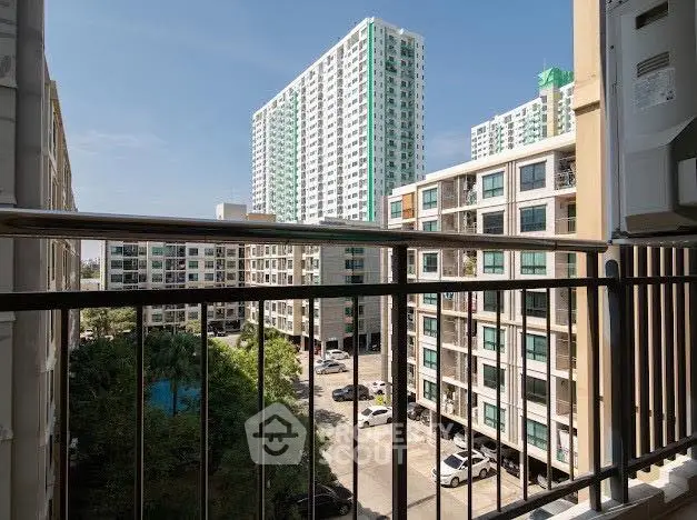 Modern urban apartment view from balcony with high-rise buildings and clear blue sky.