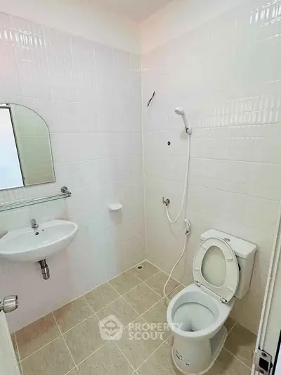 Compact bathroom with white tiles and modern fixtures, featuring a shower and toilet.