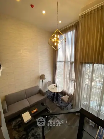 Modern living room with high ceilings and large windows offering city views.