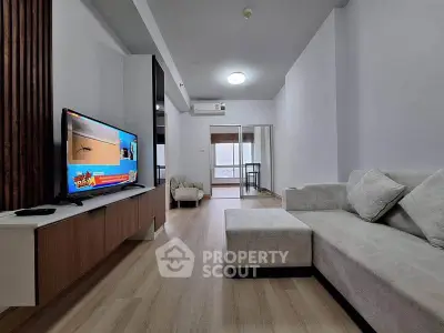 Spacious modern living room with sleek furniture and large TV, perfect for relaxation and entertainment.