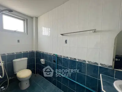Spacious bathroom with blue and white tiles, featuring a window and modern fixtures.
