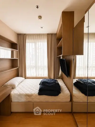Cozy modern bedroom with built-in shelves and large window offering city views.