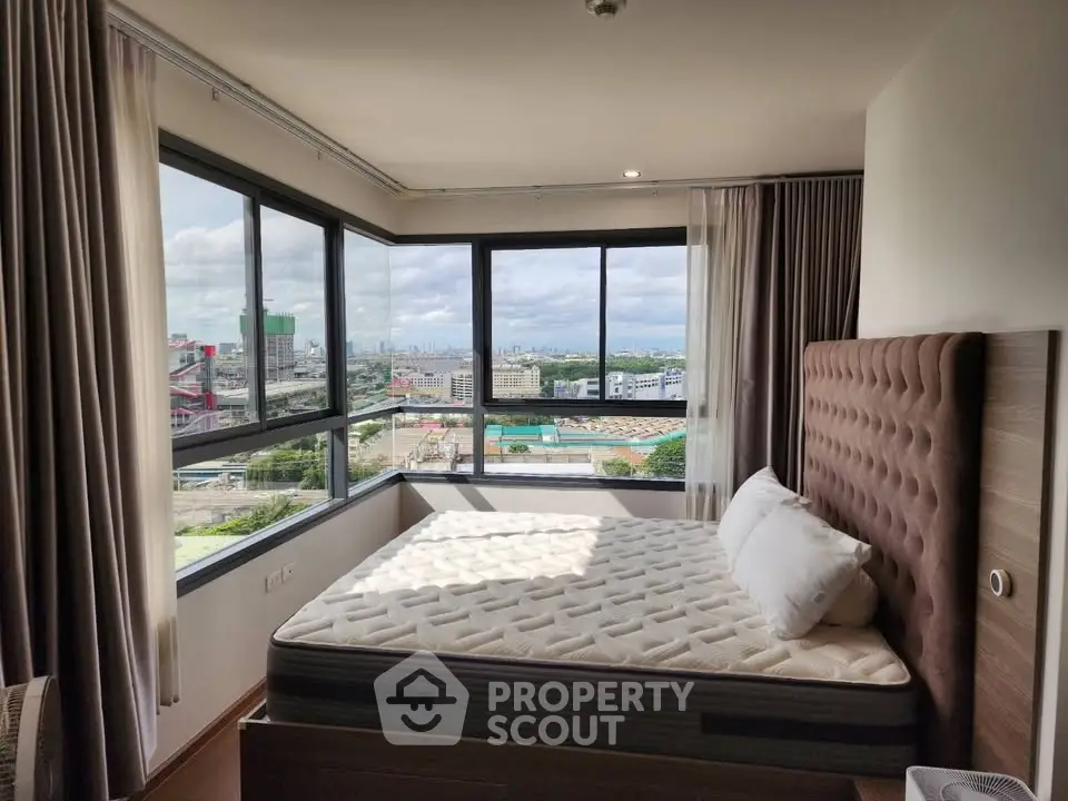 Spacious bedroom with panoramic city view and modern furnishings in high-rise apartment.