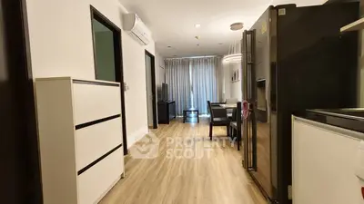 Modern apartment interior with open layout, featuring sleek kitchen and spacious living area with wooden flooring.