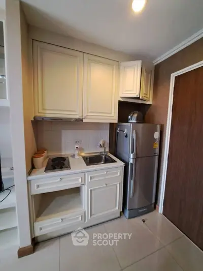 Compact kitchen with modern appliances and sleek cabinetry in cozy apartment.